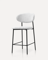 Modern upholstered bar stool with textured white fabric, ergonomic curved backrest, and matte black metal legs for kitchen islands, hotels, Airbnb properties, furnished apartments, cafés, and contemporary dining spaces.
