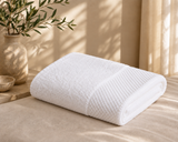 White bath towel with the Corporate Stays logo measuring for hotels, Airbnb properties, furnished apartments, spas, and luxury guest bathrooms.